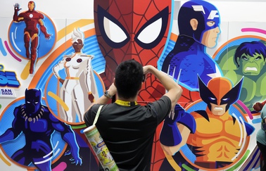 An attendee takes a picture of an illustrated wall of Marvel superhero characters during preview night for Comic-Con International, Wednesday, July 24, 2024, in San Diego. 


