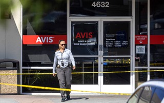 A Metro Police investigator walks out of an Avis car rental office after a fatal shooting behind the business in a shopping center at Decatur Boulevard and Sahara Avenue Saturday, Aug. 3, 2024.