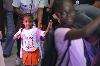 A student gets a high five from a community member during a welcome back event on the first day of school at Matt Kelly Elementary School Monday, Aug. 12, 2024.