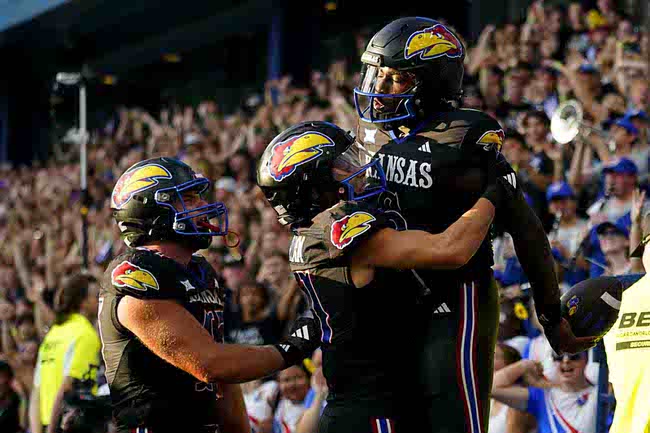 Kansas quarterback Jalon Daniels, right, celebrates after his touchdown run against UNLV with wide receiver Luke Grimm, center, and tight end Jared Casey, left, during an NCAA college football game Friday, Sept. 13, 2024, at Children's Mercy Park in Kansas City, Kan. (AP Photo/Ed Zurga)