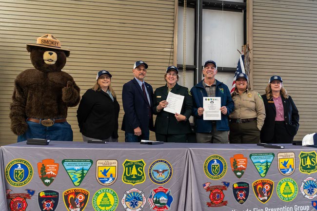 From left, Smokey Bear, Senior Advisor for Resources, U.S. Fish and Wildlife Service, Pacific Southwest Region, Kaylee Allen, BLM State Director, Jon Raby, USDA Forest Service Intermountain Regional Forester, Mary Farnsworth, Governor Joe Lombardo, Nevada State Forester/Firewarden, Kacey KC and NRCS State Conservationist, Heidi Ramsey pose for a photo after signing the Nevada Shared Stewardship Agreement in Las Vegas, Nevada on Friday, November 15, 2024.