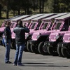 Tourists stop to take photos of Pink Jeep Tours vehicles parked in the visitor center parking lot in Tusayan, Ariz. 