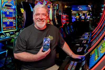 A casino customer displays the Koin app while sitting at a slot machine. App users can scan a QR code to transfer their choice of a monetary amount to gaming devices.