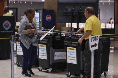A poll worker helps a voter use a ballot tabulator during primary election early voting at Meadows Mall Thursday, June 4,&nbsp;2026.