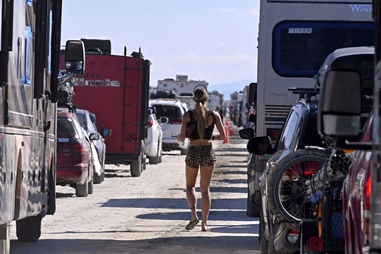 A woman walks between vehicles exiting the Burning Man festival in Black Rock Desert, Nev., on Sept. 5, 2023, after mass torrential rains closed roads and stranded thousands of attendees — one of several crises chronicled in “The Man Will Burn,” a new four-part HBO documentary series premiering Thursday, July 9,&nbsp;2026.